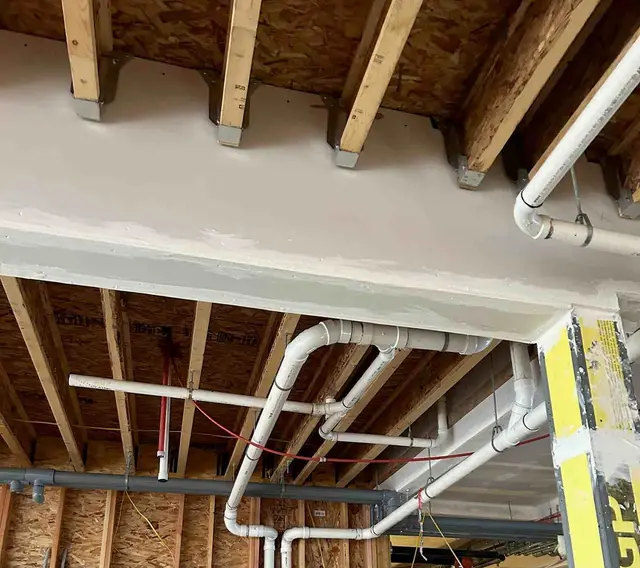 PVC drain line runs through floor joists for new construction plumbing in Boring OR – Efficiency Plumbing